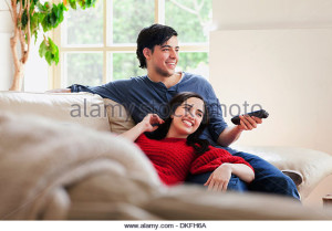 young-couple-watching-tv-on-living-room-sofa-dkfh6a